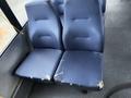 Two blue fabric seats from a 2017 Chevrolet Express with visible wear and tear showing torn fabric on the sides