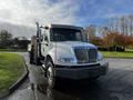 A 2013 International DuraStar 4300 truck with a white cab and a flatbed, featuring multiple lights on the roof and a black front bumper