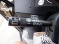 A close-up of a control lever in a vehicle featuring a low and high beam switch a turn signal indicator and a washer spray button