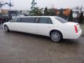 A white 2008 Cadillac limousine with a sleek design elongated body and chrome wheels parked on a wet surface