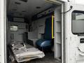 A 2016 Chevrolet Express interior showing a blue driver's seat and storage cabinets with packages on the floor