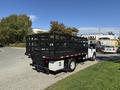 A 2016 Ford F-350 SD with a black flatbed and railing system parked on a gravel surface