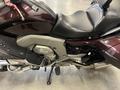 A 2013 BMW K1600GTL motorcycle in dark maroon and silver with a sleek design and various mechanical features visible on the side