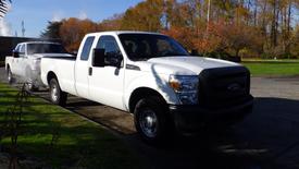 A white 2014 Ford F-350 SD pickup truck with a spacious cab and bed parked on a driveway