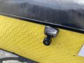 Close-up of a black and silver handle on a yellow textured surface part of a 1999 Ez-go Industrial vehicle