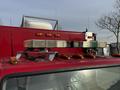 A red 1994 Freightliner FL80 with a light bar and multiple antennas on the roof and orange lights along the edge