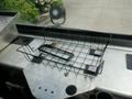 A black wire basket sits on a metallic surface with two adhesive pads attached to its base