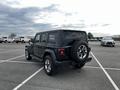 A black 2019 Jeep Wrangler parked with a spare tire mounted on the rear and a boxy, rugged design featuring large tires and prominent fenders