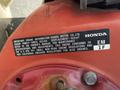 A red air compressor with a label detailing engine information and specifications, indicating it is from Honda Motor Co. with a displacement of 163 cm³