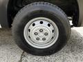 Close-up of a silver steel wheel with six lug nuts mounted on a black tire labeled Open Country