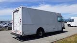 A white 2011 Ford Econoline cargo van with a boxy shape and rear loading doors parked in a lot