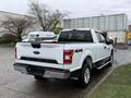 A white 2018 Ford F-150 pickup truck with a rear view showing its bed and tailgate featuring the Ford logo and 4x4 badge