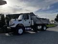 A 2011 International 7500 truck with a flatbed and side hydraulic lift, featuring a white cab and black wheels