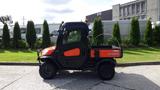 A 2018 Kubota RTV X1100C utility vehicle with an orange and black exterior features a cab and a cargo bed, designed for off-road and agricultural use