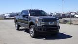 A 2017 Ford F-350 Super Duty in a dark color with a prominent front grille and chrome details parked with its headlights on