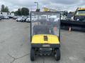 A yellow 2000 Ez-go Industrial 800 golf cart with a transparent enclosure and a checkerboard pattern on the roof