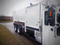 A 2008 International 7400 garbage truck with a white exterior and a side-loading compartment is parked in an outdoor setting