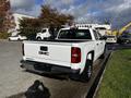 A white 2017 GMC Sierra 1500 pickup truck parked with its tailgate down showcasing the GMC logo on the rear