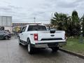 A 2018 Ford F-150 pickup truck is parked with its rear facing the viewer showcasing a white exterior and 4x4 badge