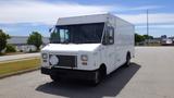 A white 2011 Ford Econoline van with a boxy shape and a blank front grill parked on a concrete surface