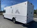 A white 2006 Workhorse W42 delivery truck with a boxy design and a rear roll-up door parked on the side of a road