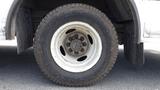 A close-up of a dirty white wheel with a metal rim from a 2011 Ford Econoline showing the tire tread and lug nuts