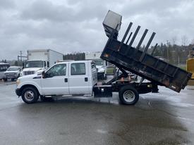 A 2011 Ford F-350 SD with a dump bed raised, showcasing its cargo area and flatbed design