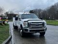 A 2014 Ford F-350 SD in white with a utility bed and several lights on the roof parked on a wet road