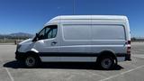 A 2016 Mercedes-Benz Sprinter van in profile view with a white exterior and black detailing on the lower body