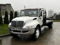 A 2011 International DuraStar 4300 truck with a white cab and a flatbed rear visible in the foreground