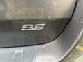 Close-up of the rear emblem of a 2013 Toyota Sienna showing the letters SE with droplets of water on the surface