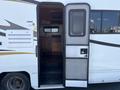 A 2012 Ford Econoline with an open door revealing the interior featuring wooden cabinetry and steps leading inside