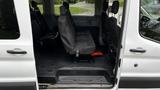 Interior of a 2017 Ford Transit showing driver and passenger seats along with a row of upholstered seats and floor mats