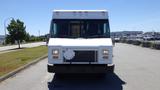 A white 2006 Ford Econoline with a boxy design facing forward and a missing front license plate