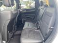 Interior view of the backseat of a 2018 Jeep Grand Cherokee featuring black leather and suede upholstery with seat belts and armrest