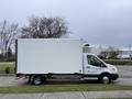 A 2018 Ford Transit truck with a large white cargo box attached to the rear parked on a paved surface