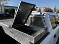 A 2017 Ford F-150 with an open aluminum truck bed toolbox featuring a diamond plate design and storage compartments inside