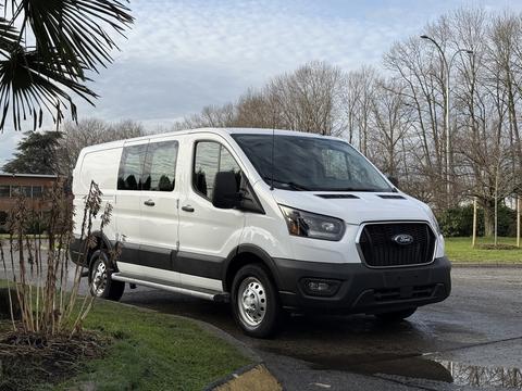 A white 2023 Ford Transit van with black trim and sliding side doors parked on a street