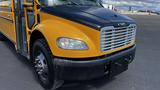 A yellow 2014 Freightliner Thomas diesel school bus with a black front hood and chrome grille visible in the foreground