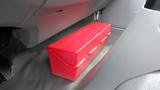 A red toolbox placed on the floor of a vehicle's cabin