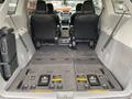 Interior view of a 2013 Toyota Sienna with black leather seats and slid back second row seats revealing the cargo area with flat folding seats