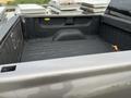 A 2013 Chevrolet Silverado Hybrid with an open truck bed showing a dark, textured surface and some scattered leaves