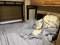 A disheveled bed with wrinkled bedding and a pile of blankets in the bedroom of a 2008 Newmar Canyon Star Class A Motorhome