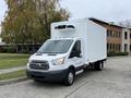 A 2018 Ford Transit truck with a white box cargo area and a refrigeration unit on top parked on a driveway