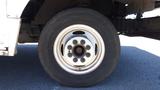 A close-up of a wheel from a 2006 Ford Econoline featuring a white rim and a black tire with visible tread patterns