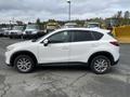 A white 2016 Mazda CX-5 parked with a profile view showcasing its sleek design and alloy wheels