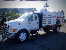 A white 2006 Ford F-650 truck with a large utility body and a side-mounted compartment featuring multiple ventilation grills