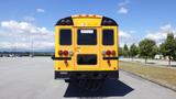 A yellow 2014 International 3000 school bus viewed from the back with two red lights and a sign displayed in the rear window