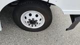 A white wheel of a 2006 Ford Econoline with multiple lug nuts and a black tire showing signs of wear