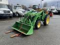 A green 2003 John Deere 790 tractor with a front loader attachment and forks attached to the bucket